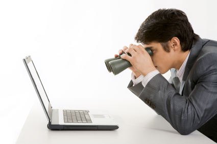 Portrait of businessman holding binoculars and looking at laptop