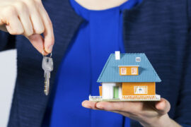 real estate agent with key and house model on hand