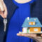 real estate agent with key and house model on hand